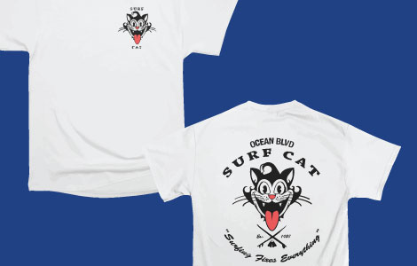 The front and back of a T-Shirt is shown with the surf cat design. The surf cat is a grinning black cat head with its red tongue sticking out.